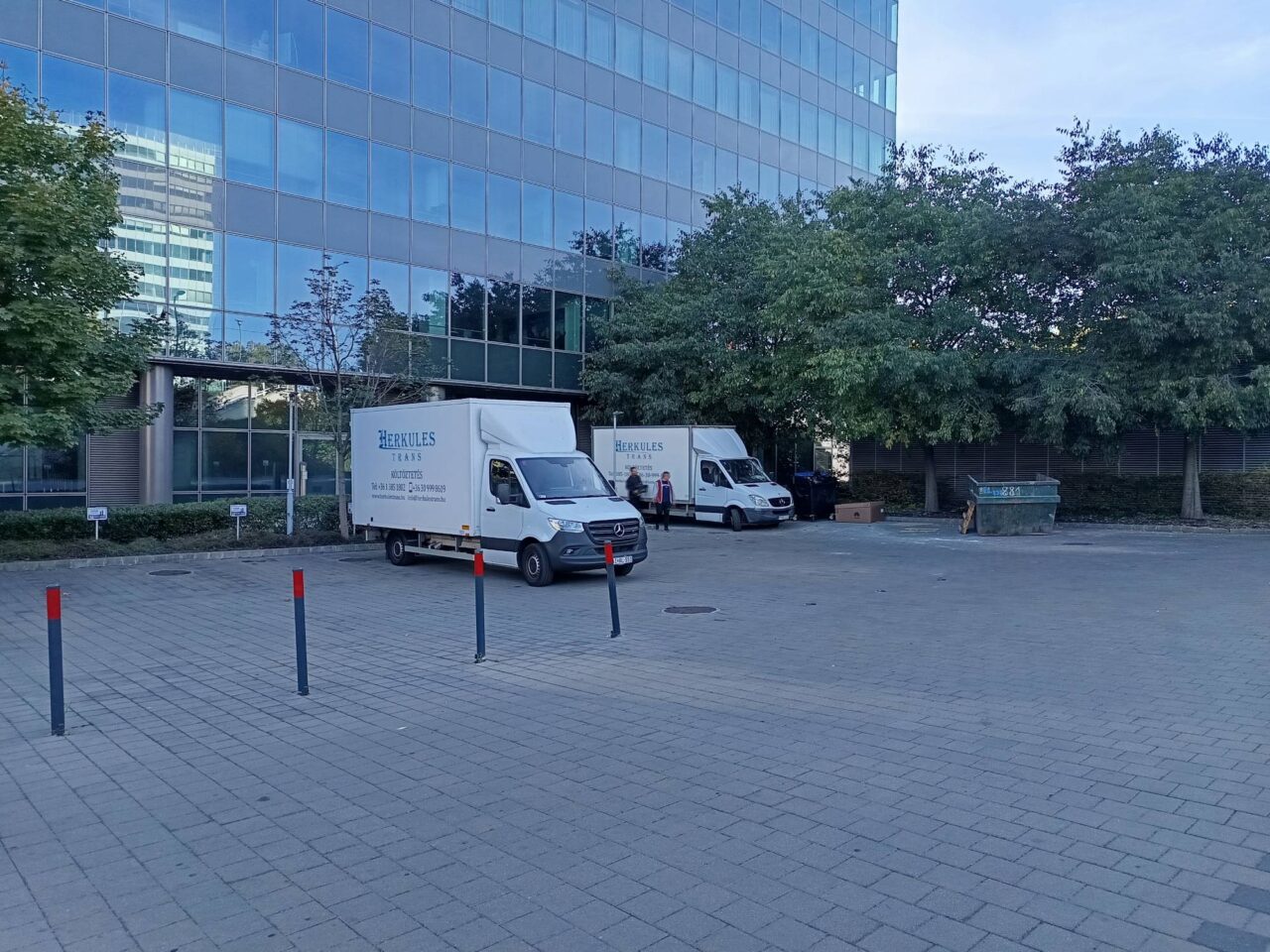 herkules-trans-ket-teherauto-uveghazas-parkolo Two Herkules-Trans trucks in the car park of a glass-fronted office building