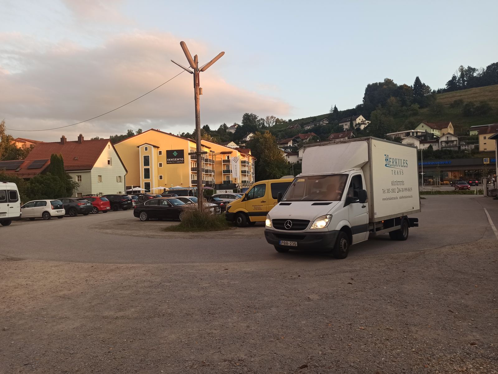 Herkules-Trans teherautó kisvárosi parkolóban, költöztetés Herkules-Trans költöztető teherautó egy dombvidéki kisváros parkolójában, költöztetés közben